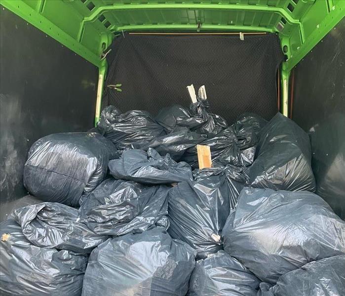 A green SERVPRO truck packed with bags of debris for safe disposal