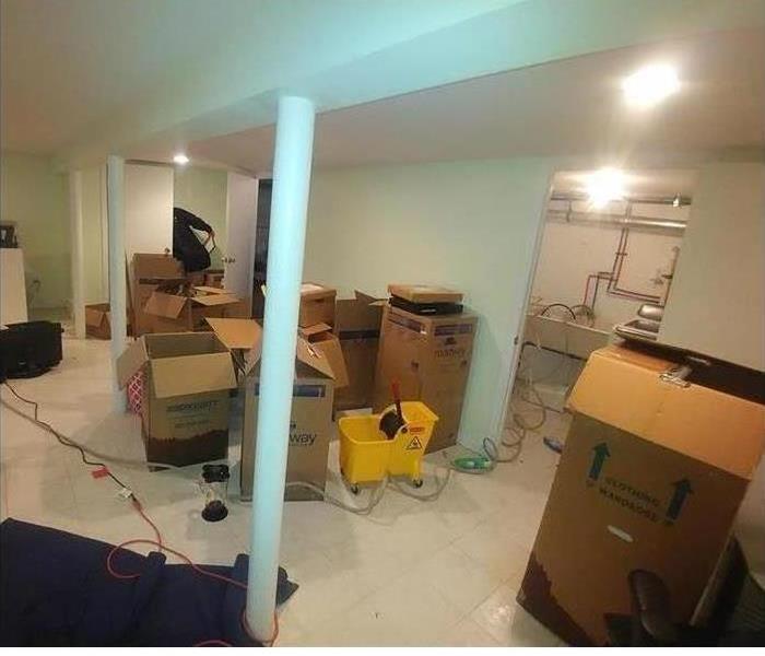 A basement with card board boxes and flood damage